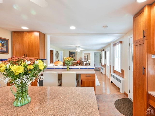 kitchen featuring a peninsula, radiator heating unit, light countertops, and brown cabinets