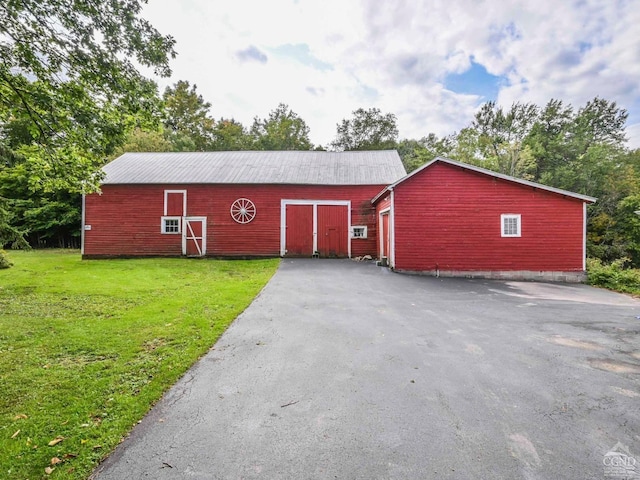 view of barn with aphalt driveway and a yard