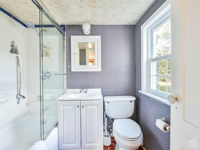 full bath with enclosed tub / shower combo, toilet, vanity, and wallpapered walls