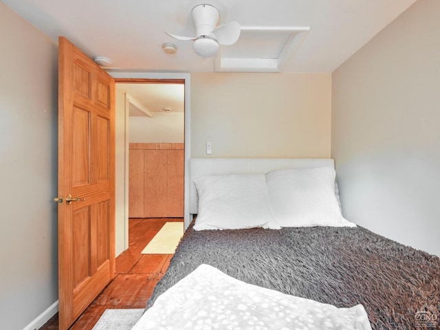 bedroom with attic access, a ceiling fan, and wood finished floors