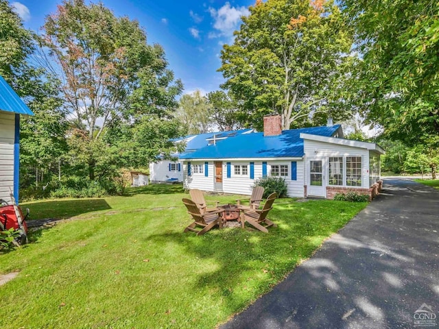 view of front of home featuring an outdoor fire pit, brick siding, a front yard, and a chimney