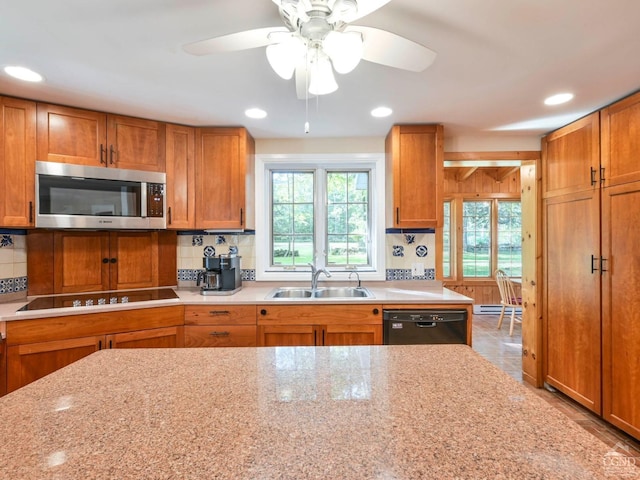 kitchen with a wealth of natural light, backsplash, black appliances, and a sink