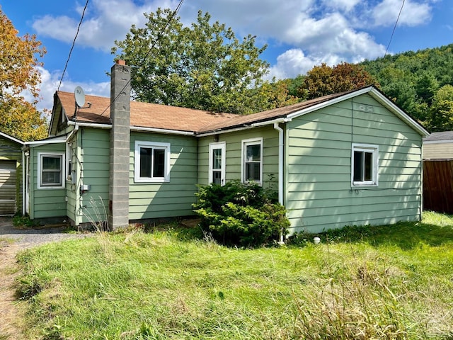 rear view of house featuring a yard and a chimney