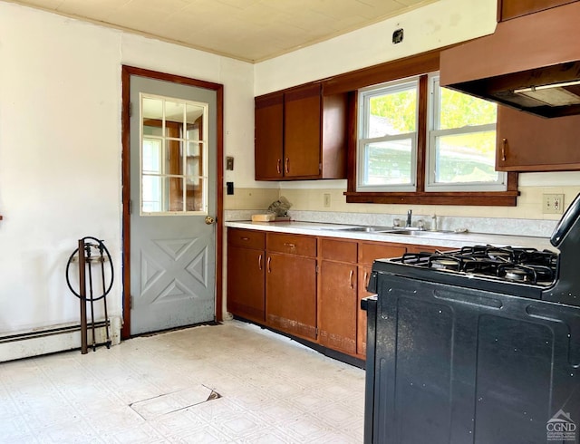 kitchen with brown cabinets, light floors, light countertops, black range with gas cooktop, and exhaust hood