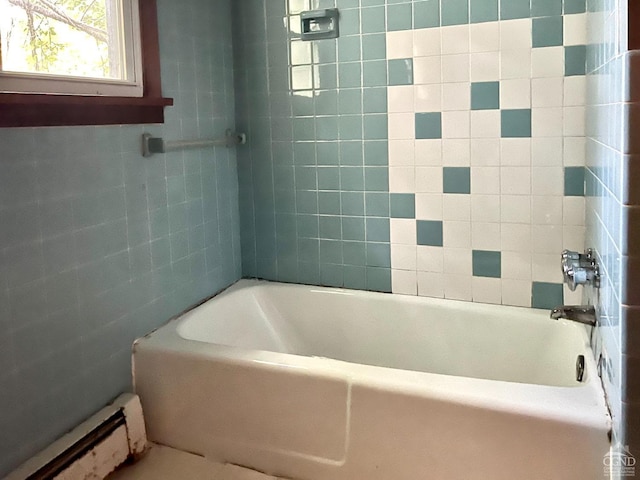 bathroom with a tub to relax in, a baseboard heating unit, and tile walls