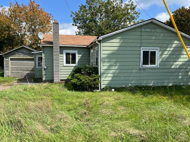 rear view of house with a chimney and a detached garage