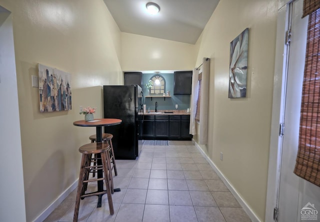 hallway with sink, lofted ceiling, and light tile patterned flooring