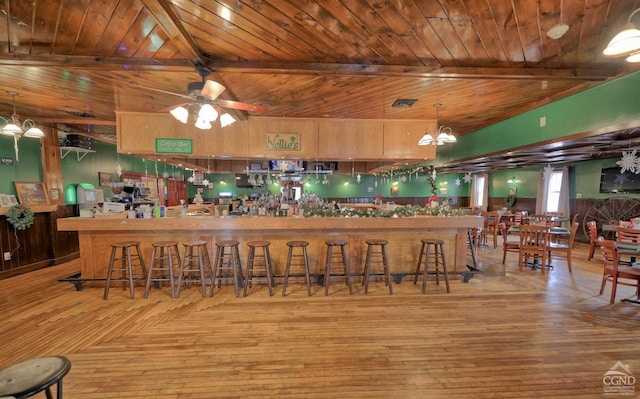 bar with pendant lighting, ceiling fan with notable chandelier, light hardwood / wood-style floors, and wooden ceiling