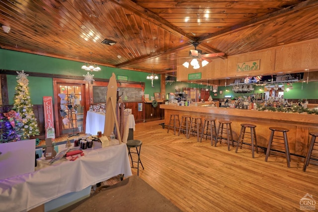 dining space featuring ceiling fan, light hardwood / wood-style floors, wooden ceiling, and bar area