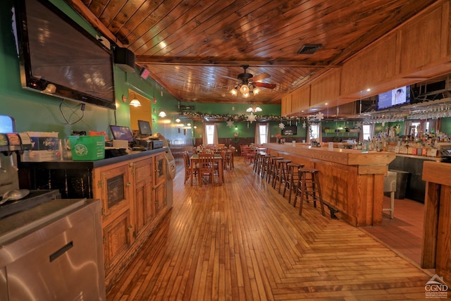 kitchen with wood ceiling, ceiling fan, light hardwood / wood-style floors, a kitchen island, and a breakfast bar area