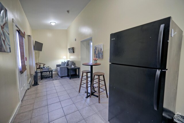 kitchen with a towering ceiling, black refrigerator, and light tile patterned flooring