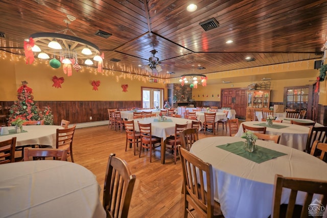 dining room featuring ceiling fan, a baseboard heating unit, wood walls, light hardwood / wood-style floors, and wood ceiling