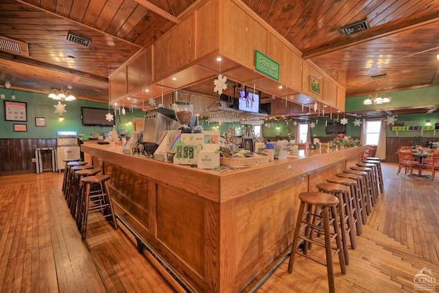 bar with pendant lighting, light hardwood / wood-style floors, and wooden ceiling