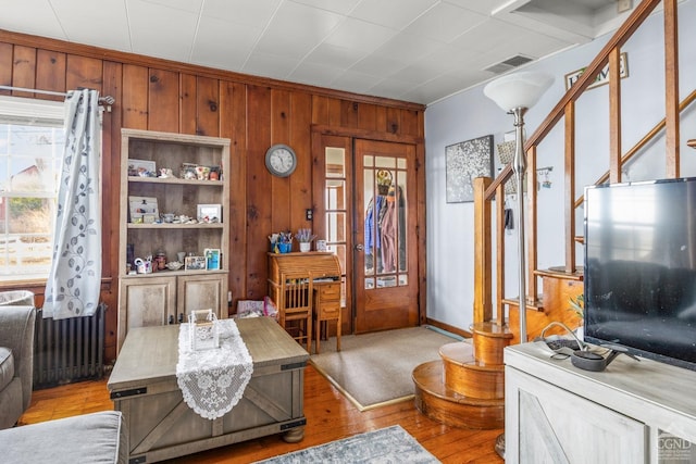 interior space with visible vents, light wood-style flooring, radiator, and wood walls