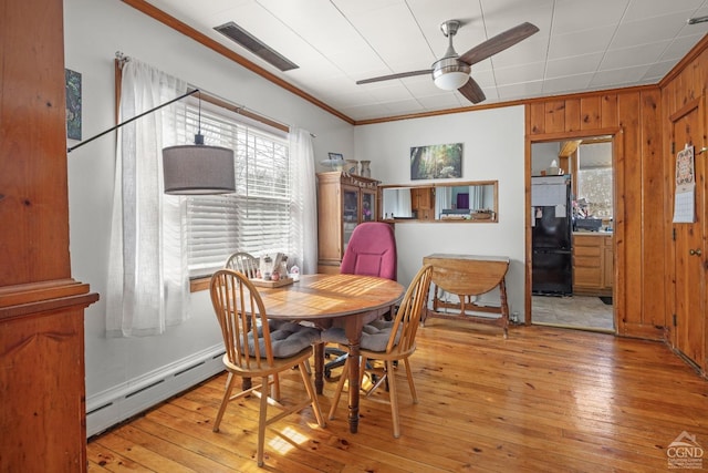 dining area featuring visible vents, a ceiling fan, light wood-style floors, baseboard heating, and crown molding