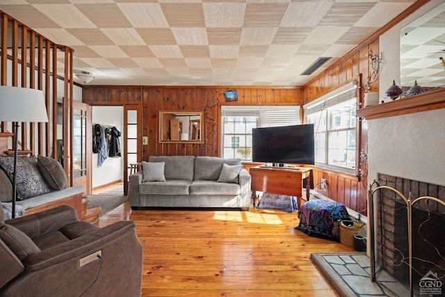 living area with a fireplace with raised hearth, hardwood / wood-style flooring, and wooden walls