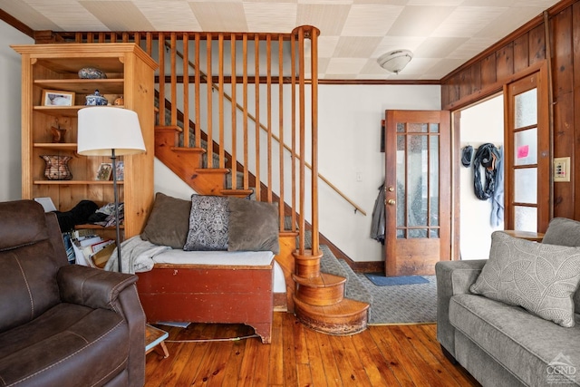 living area with hardwood / wood-style floors, baseboards, ornamental molding, and stairs