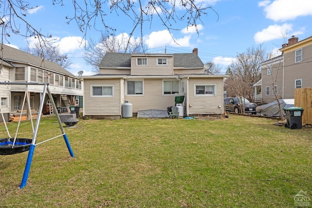 back of property with a yard, a trampoline, and roof with shingles