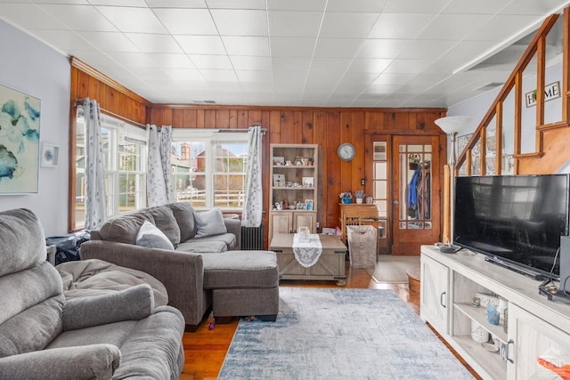 living room featuring wooden walls, visible vents, and wood finished floors