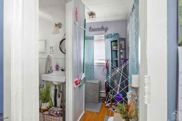 bathroom with a baseboard radiator, wood finished floors, and a sink