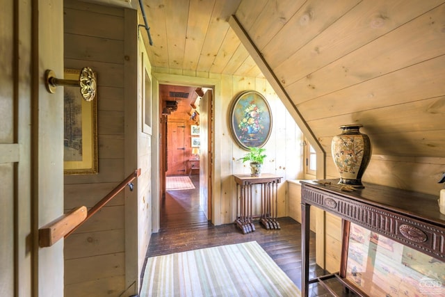 hall with wood walls, dark hardwood / wood-style flooring, wooden ceiling, and vaulted ceiling