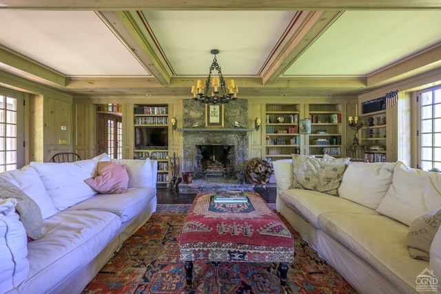 living room with an inviting chandelier, built in shelves, ornamental molding, a fireplace, and dark hardwood / wood-style flooring