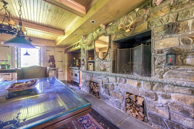 interior space with beam ceiling, a stone fireplace, high end stainless steel range, and wooden ceiling