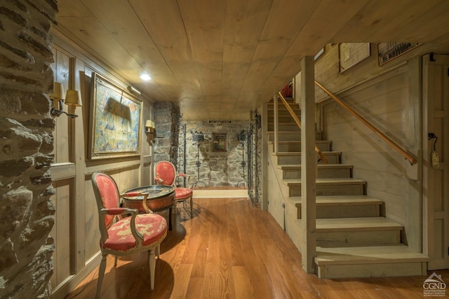 basement featuring wood ceiling, wooden walls, and light hardwood / wood-style floors