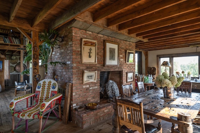 dining room featuring hardwood / wood-style floors, a fireplace, beam ceiling, wood ceiling, and brick wall