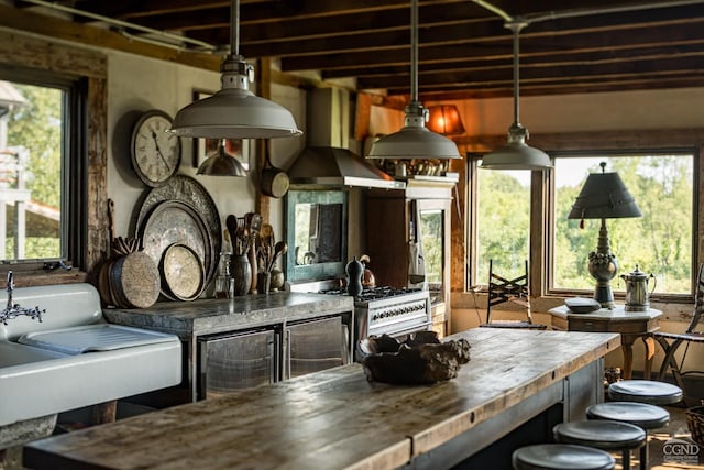 interior space with a wealth of natural light, stainless steel range, exhaust hood, and wooden counters