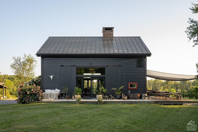 back of house with an outdoor structure and a lawn