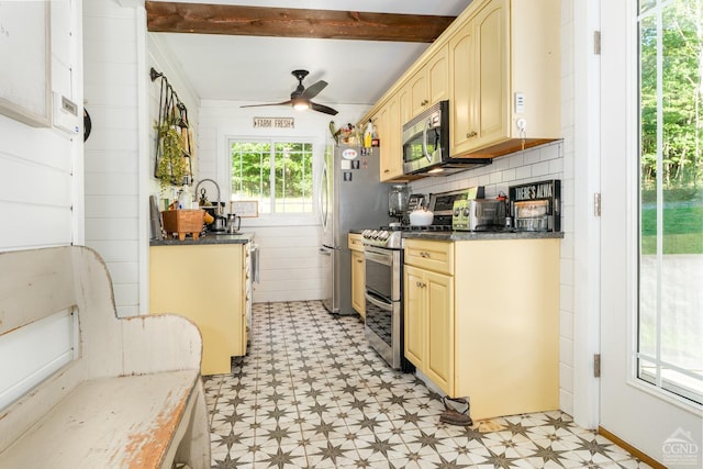 kitchen with appliances with stainless steel finishes, backsplash, ceiling fan, dark stone countertops, and beamed ceiling