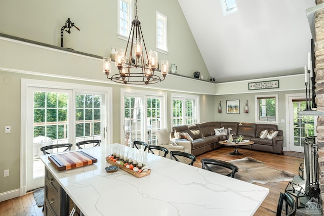 dining room featuring a fireplace, light hardwood / wood-style flooring, high vaulted ceiling, and a notable chandelier