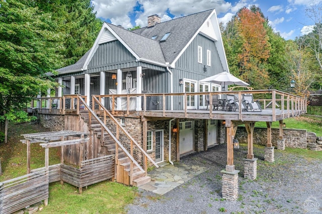 rear view of house featuring a wooden deck and a garage