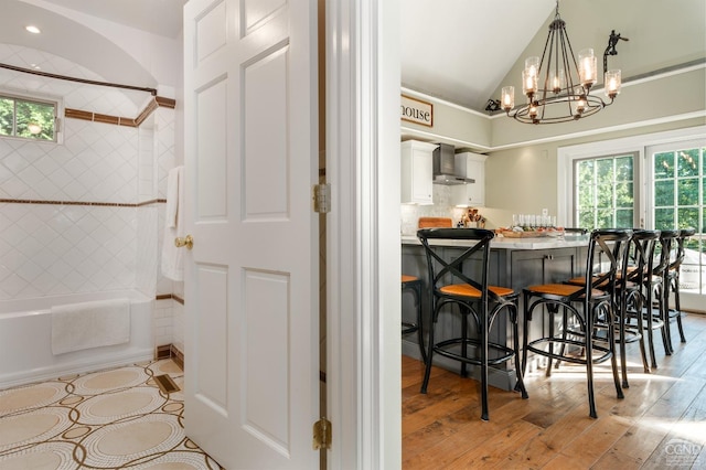 dining area with a notable chandelier, light wood-type flooring, and vaulted ceiling