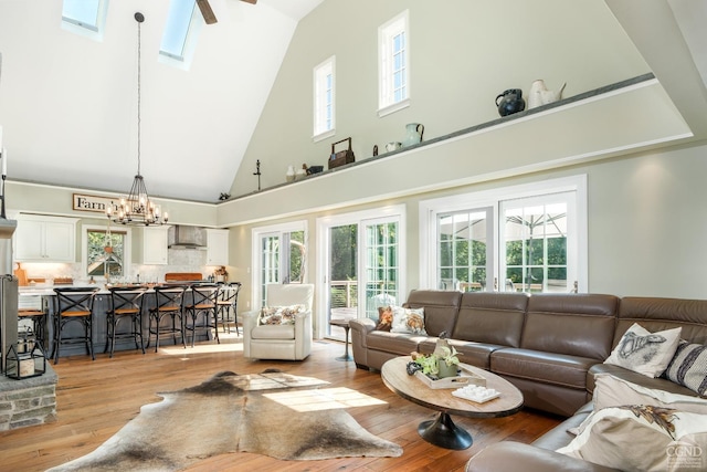 living room featuring a skylight, a wealth of natural light, high vaulted ceiling, and light hardwood / wood-style floors