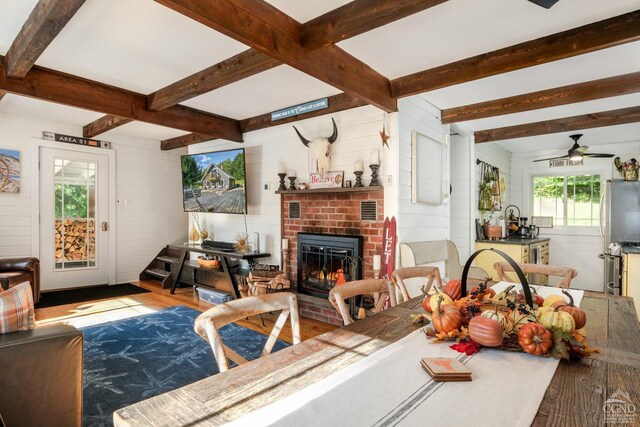 living room with beam ceiling, light wood-type flooring, ceiling fan, and wooden walls