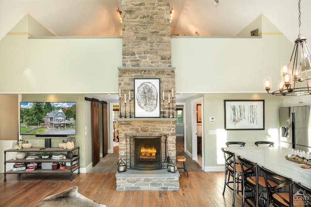 living room with hardwood / wood-style flooring, a stone fireplace, and a towering ceiling