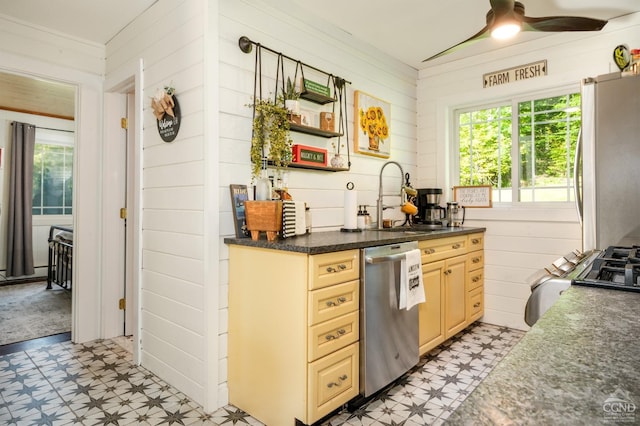 kitchen with light brown cabinets, sink, stainless steel appliances, and wooden walls