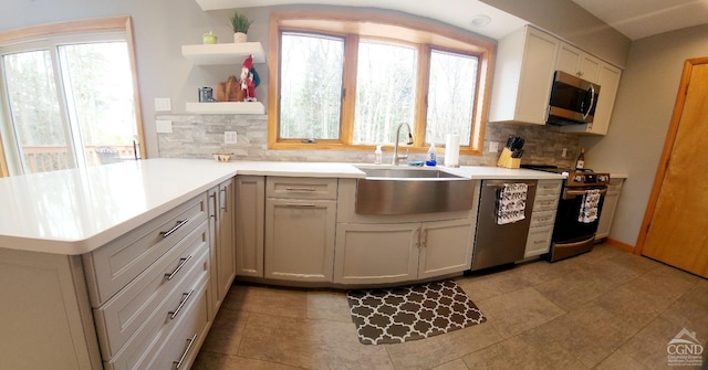 kitchen featuring open shelves, stainless steel appliances, backsplash, and a sink