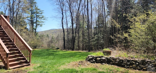 view of yard featuring a wooded view and stairway