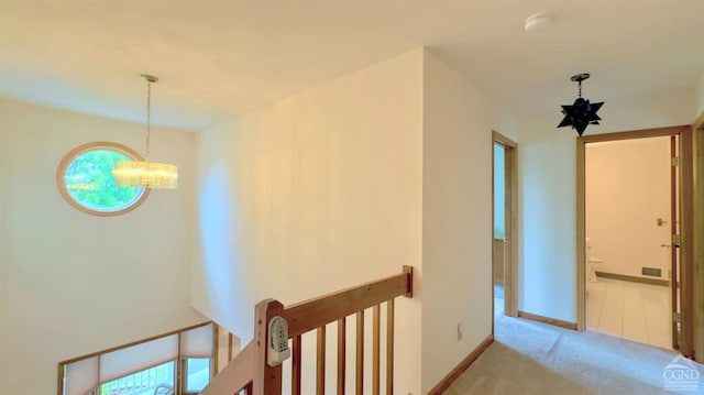 hall featuring an inviting chandelier and light colored carpet