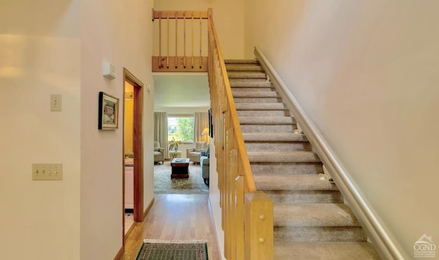 stairs featuring hardwood / wood-style flooring and a high ceiling