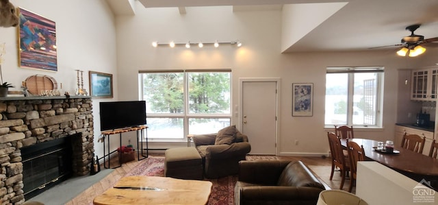 living room featuring a stone fireplace and ceiling fan