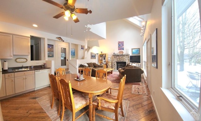 dining space featuring a healthy amount of sunlight, a stone fireplace, light wood-type flooring, and sink