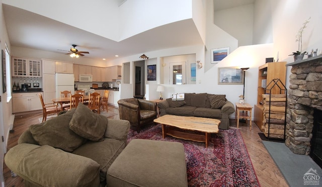 living room with hardwood / wood-style floors, ceiling fan, and a high ceiling