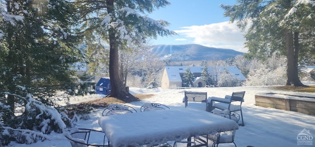 snow covered patio with a mountain view