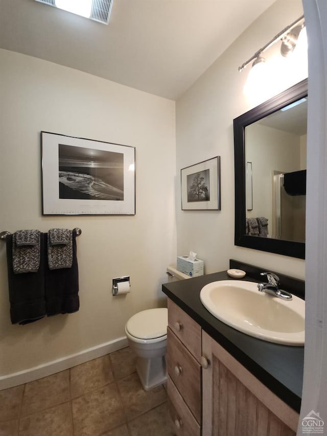 bathroom featuring tile patterned flooring, vanity, toilet, and walk in shower