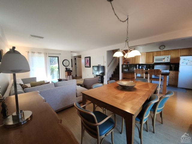 dining space with light hardwood / wood-style floors and an inviting chandelier