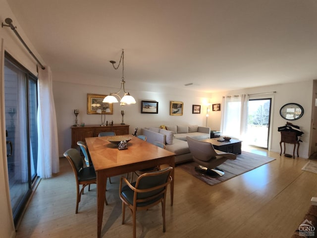 dining area with light hardwood / wood-style floors and an inviting chandelier